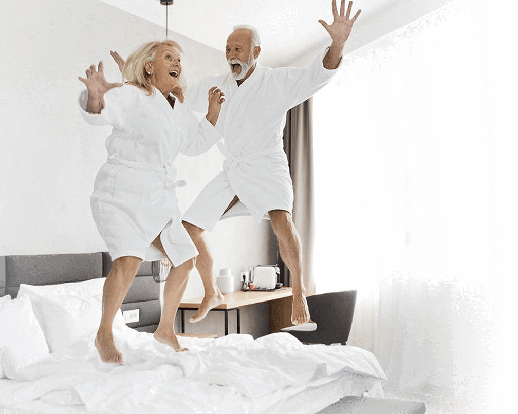 happy older couple jumping on bed